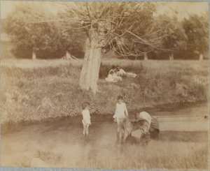 Tres niños y un perro jugando en el arroyo