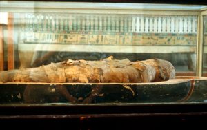 Momia envuelta en vendas y acostada en la base de un ataúd, Antiguo Egipto