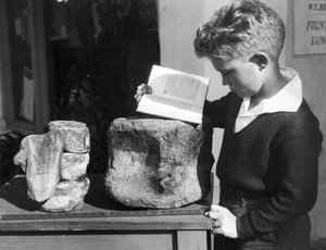 Palos Verdes, California: c.1927 Un niño estudia arqueología con el uso de una vértebra prehistórica fosilizada encontrada en las colinas cercanas.
