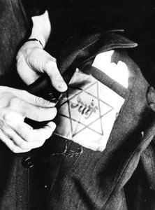 Cosiendo la estrella amarilla que identifica a un judío en una chaqueta, París ocupada por los alemanes, 1942 de Unbekannt