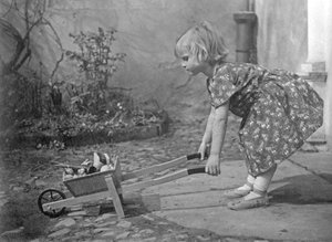 Niña pequeña jugando con una carretilla. Fotografía alrededor de 1931