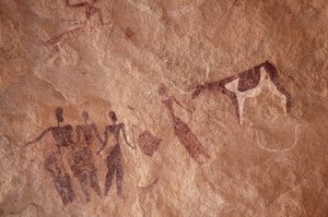 Arte rupestre, Prehistoria: Pintura rupestre de un grupo de personajes y una vaca bicolor con grandes cuernos en un refugio ornamentado, en el macizo de Uweinat, Egipto. (Período de 8000 a 3000 años a.C.). Fotografía de Unbekannt