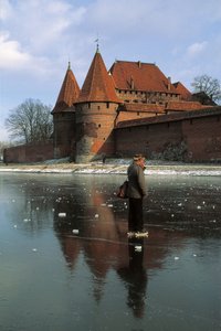 Perfil lateral de un hombre de pie en un río congelado frente a un castillo, Río Nogat, Castillo de Malbork, Malbork, Provincia de Pomorskie, Polonia