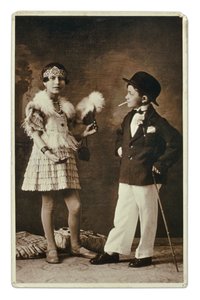 Dos niños vestidos de adulto a la moda de los años 20, la niña con traje de charlestón y él con traje, bombín y cigarrillo. Fotografía de Unbekannter Künstler
