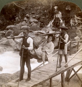 Mujer japonesa en una silla de montaña yamakago cruzando el torrencial río Daiya cerca de Nikko, Japón de Underwood and Underwood