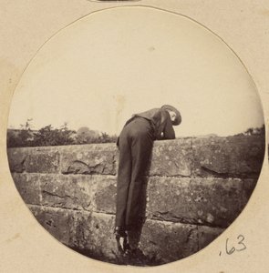 [Hombre con sombrero inclinado sobre un muro de piedra] de Unknown artist