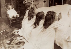 Cuatro niñas arrodilladas junto a una cama mientras rezan la oración de la tarde. de Unknown photographer