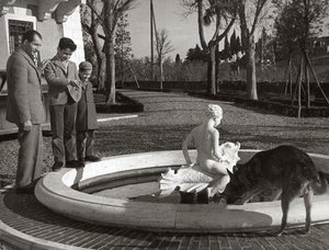 Gino Bartali con dos niños y un perro cerca de una fuente