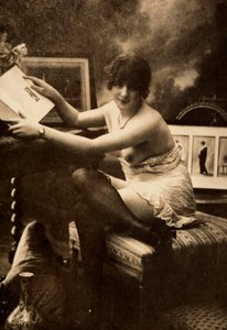 Retrato de una joven en ropa íntima, sentada a una mesa con un libro. de Unknown photographer