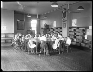 Niños escuchan a una mujer en la sala de lectura de una sucursal no identificada de la Biblioteca Pública del Borough de Queens, c.1910 (foto en blanco y negro) de William Davis Hassler