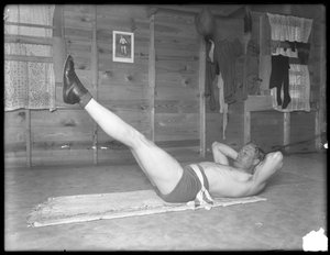 Boxeador inglés William Thomas Wells (Bombardier Billy Wells), posando en ropa de entrenamiento haciendo levantamientos de piernas, c.1911