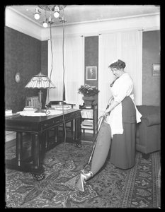Mujer no identificada demostrando el uso de la aspiradora Apex, c.1913-14