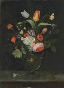 Rosas, tulipanes, un narciso y otras flores en un jarrón de vidrio, sobre un borde de piedra con un ratón de . .