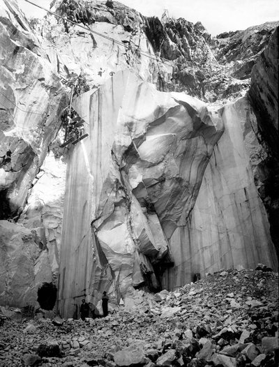 Excavadores trabajando a lo largo de una pared empinada de una cantera de mármol en los Alpes Apuanos, Toscana. (foto en blanco y negro) de A. Corsini