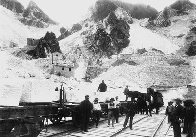 Excavadores frente a un convoy ferroviario cargado con bloques de mármol en Ravaccione, en los Alpes Apuanos (foto en blanco y negro) de A. Corsini