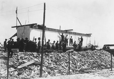 Varios hombres alrededor de un enorme bloque de mármol ya cuadrado, recién transportado al valle desde las canteras en los Alpes Apuanos (foto en blanco y negro) de A. Corsini