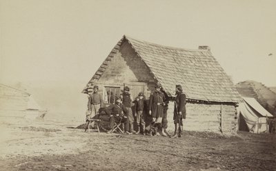 Un grupo de soldados y dos jóvenes, uno afroamericano, fuera de las cabañas de troncos, 1861-65 de American Photographer
