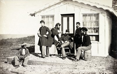 Cinco soldados de la Guerra Civil reunidos en el porche de tierra fuera de una casa, joven afroamericano sentado cerca de ellos, 1861-65 de American Photographer