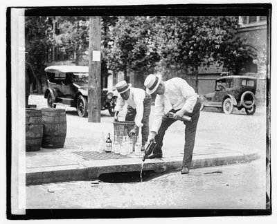 Dos hombres vertiendo licor en una alcantarilla, 8 de julio de 1921 de American Photographer