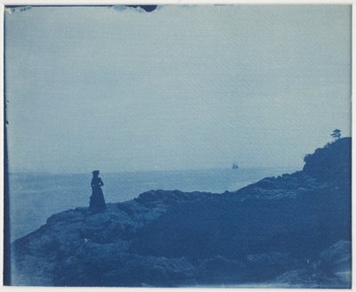 Mujer observando goleta desde un promontorio rocoso de American Photographer