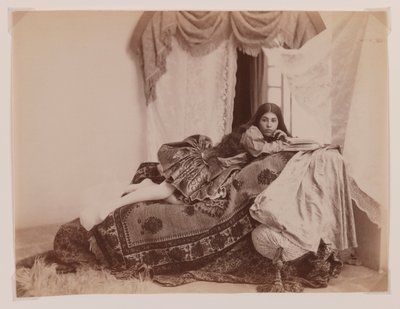 Foto de estudio de una dama reclinada leyendo un libro de Antoin Sevruguin