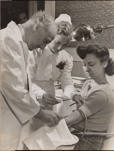 [Médico y enfermera insertan una aguja en el brazo de una mujer] de Arnold Eagle