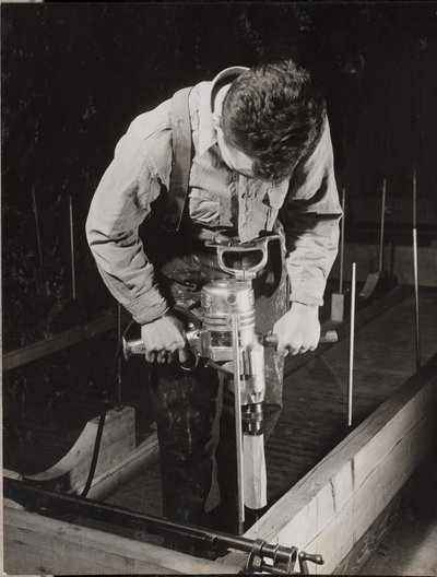 [Un hombre utiliza una máquina manual para trabajar con un trozo de madera]. de Arnold Eagle