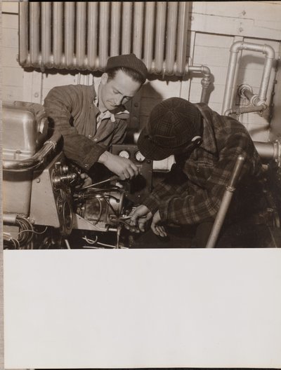 [Dos hombres trabajan en una máquina utilizando un destornillador y una llave inglesa] de Arnold Eagle