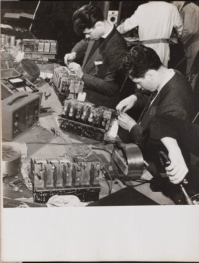 [Dos jóvenes vestidos con americana trabajan con radios] de Arnold Eagle