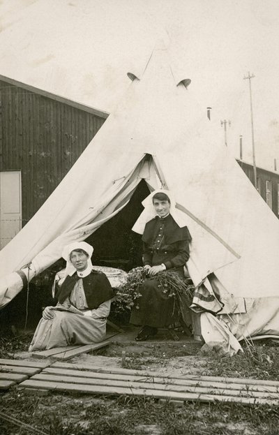 La hermana Eleanor Wibmer Jeffries y la hermana Nellie Constance Morrice (derecha) fuera de su tienda en el Hospital General Australiano No. 3 con flores recogidas de la orilla del Somme, c. junio de 1917 (foto en blanco y negro) de Australian Photographer