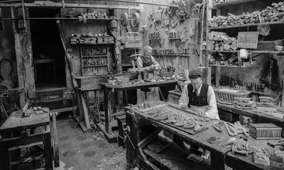 Artesanos en un banco de trabajo fabricando pequeños objetos de madera que no parecen... de Bernard F. Rogers