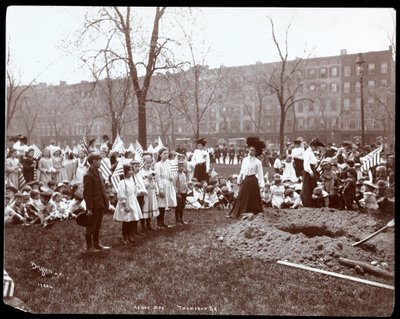 Adultos y niños sosteniendo banderas alrededor de un hoyo recién cavado para plantar un árbol en el Día del Árbol en Tompkins Square Park, Nueva York, 1904 de Byron Company