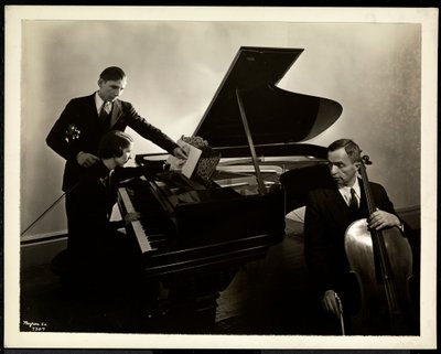 Mujer ciega, Srta. Harding, en el piano instruyendo a dos hombres ciegos en el violín y el violonchelo, 1936 de Byron Company