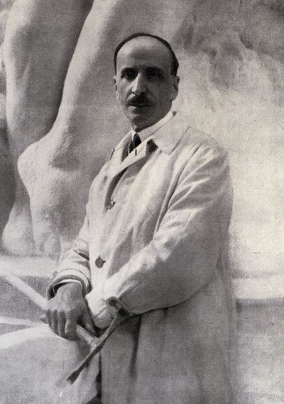 Retrato de tres cuartos del escultor Edoardo Rubino con martillo en mano. En el fondo se puede distinguir una escultura de Carlo Gherlone
