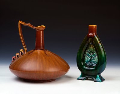 Una jarra de cerámica Linthorpe de forma globular comprimida con esmalte caramelizado, verde y carmesí y un jarrón de cerámica Linthorpe con decoración de capullo de flor perforada y esmaltes moteados verdes, azules y marrones de Christopher Dresser