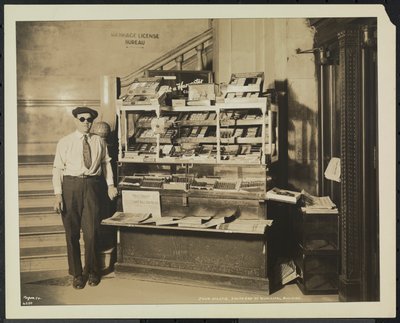 Vendedor de periódicos ciego, John Martie, en su puesto en el extremo sur del Edificio Municipal, Nueva York de Company Byron