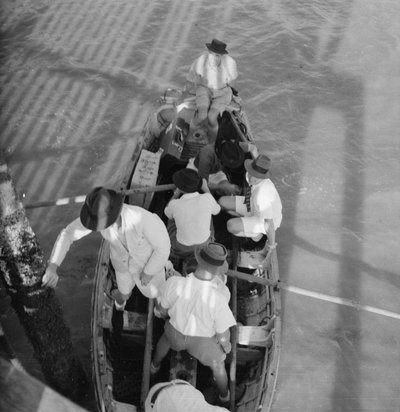 Siete hombres en un bote, posiblemente un esquife de la Marina Real, junto a un embarcadero en el club náutico de la Real Fuerza Aérea en Seletar, Singapur. de David Watkin Waters