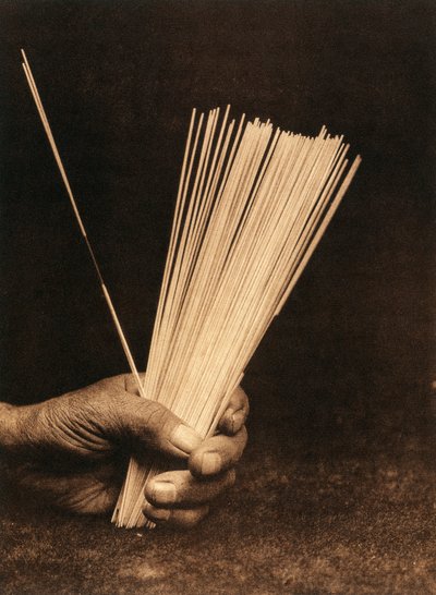 Primer plano de la mano de un indio de la tribu o pueblo Hupa sosteniendo unas varillas de adivinación. de Edward Sheriff Curtis