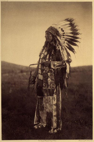Halcón alto. Conjunto de guerrero vestido para una gran ocasión: camisa de cuero, polainas, mocasines, funda de pipa (todo bordado con piquantes de cerdo-épica), tocado de guerra con plumas de águila, bastón con cabeza de piedra, con una cabellera. Hight H de Edward Sheriff Curtis