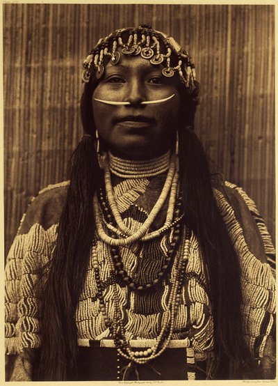 Chica Wishham. Esta chica lleva un pesado vestido de ante adornado con perlas. El atributo ornamental indispensable de una persona bien nacida era la concha dental en el tabique nasal. El tocado está hecho de conchas, caracolas y cuentas de chatarra, así c de Edward Sheriff Curtis