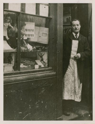 Un tendero de pie en la puerta de su tienda de English Photographer