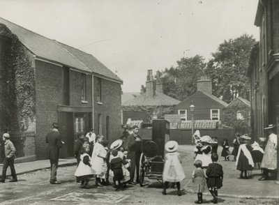 Multitud de niños se reúne alrededor de un órgano de calle de English Photographer