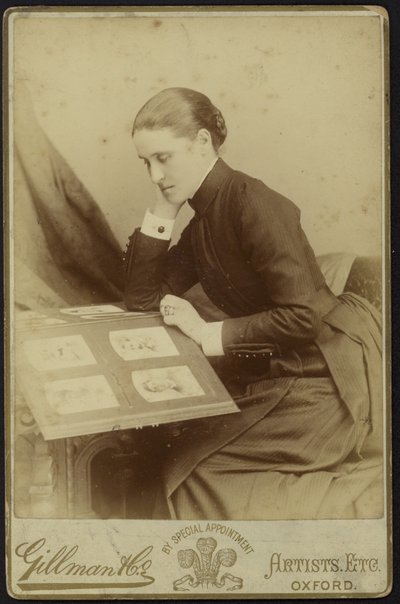 Figura de una mujer sentada inspeccionando un álbum de fotografías de English Photographer