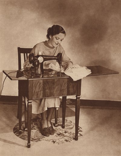 Ama de casa trabajando con la máquina de coser, mediados de la década de 1930 (fotografía en blanco y negro). de English Photographer