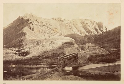 Vistas sobre el Ferrocarril del Pacífico, de la vía férrea que cruza un río en un puente de vigas, con montañas más allá de English Photographer