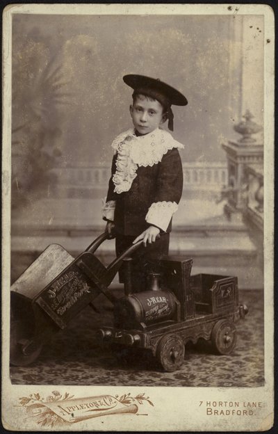 Retrato de un niño pequeño posando con un carrito de mano de English School