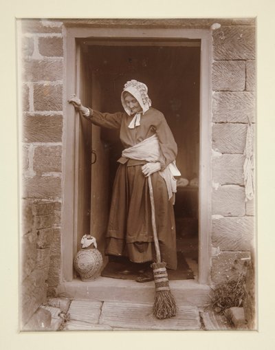 Una anciana con una botella de levadura en la puerta de una cabaña de Frank Meadow Sutcliffe