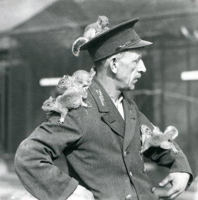 Un cuidador de segunda clase con cuatro ardillas grises jóvenes trepando por su sombrero y chaqueta, zoológico de Londres de Frederick William Bond
