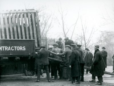 Una multitud de espectadores observa mientras un rinoceronte es descargado de un camión por los cuidadores en el Zoológico de Londres en 1924 de Frederick William Bond