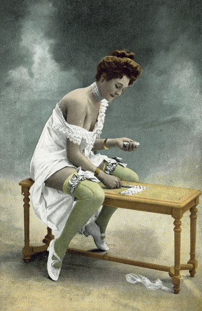 Chica con medias y pecho expuestos jugando paciencia en un taburete de madera de French Photographer